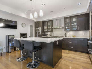 Experience modern luxury in this stunning kitchen, featuring sleek dark wood cabinetry and a spacious quartz island perfect for entertaining.