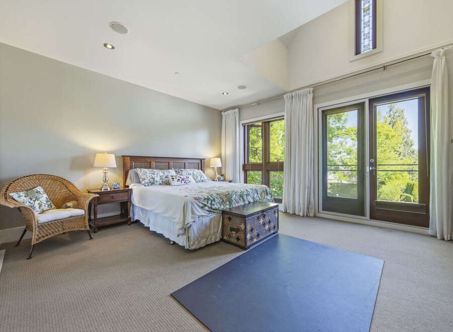 Experience luxurious living in this spacious master bedroom, featuring a comfortable king-size bed with a floral comforter and a decorative storage trunk at the foot.