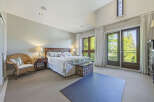 Experience luxurious living in this spacious master bedroom, featuring a comfortable king-size bed with a floral comforter and a decorative storage trunk at the foot.