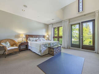 Experience luxurious living in this spacious master bedroom, featuring a comfortable king-size bed with a floral comforter and a decorative storage trunk at the foot.