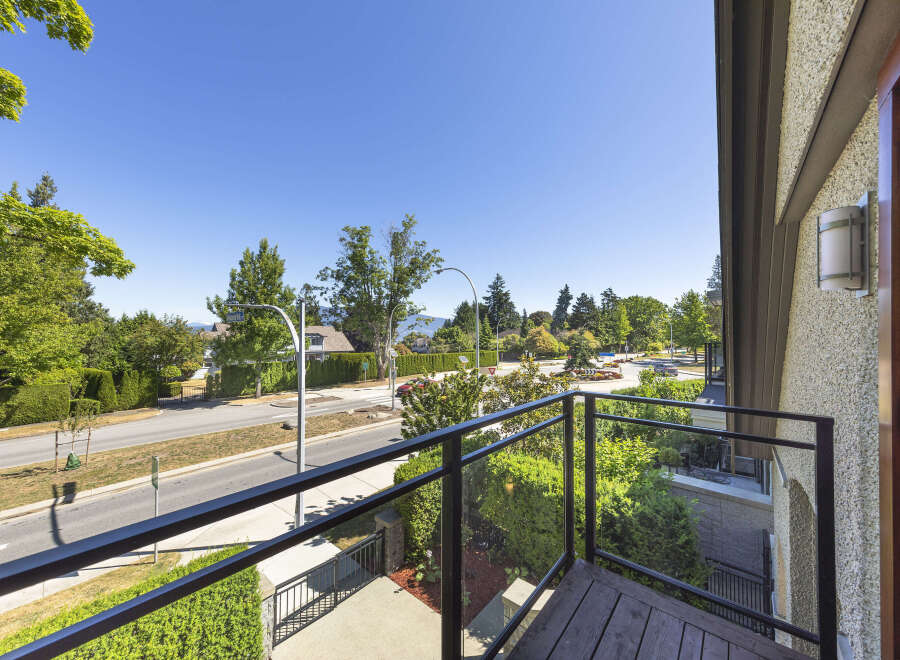 Enjoy the stunning views from this balcony overlooking a tree-lined street and distant mountains.