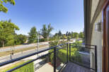 Enjoy the stunning views from this balcony overlooking a tree-lined street and distant mountains.