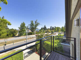 Enjoy the stunning views from this balcony overlooking a tree-lined street and distant mountains.