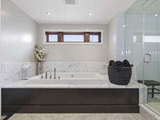 Indulge in luxury with this stunning bathroom featuring a deep soaking tub set against elegant marble countertops.