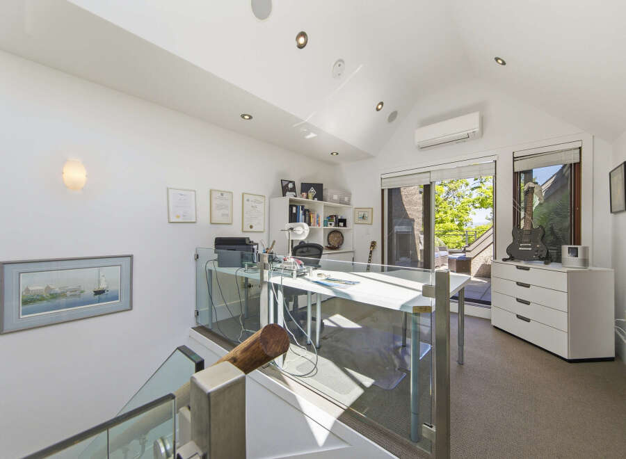 This modern home office features a sleek white desk with glass partitions, perfect for productivity.