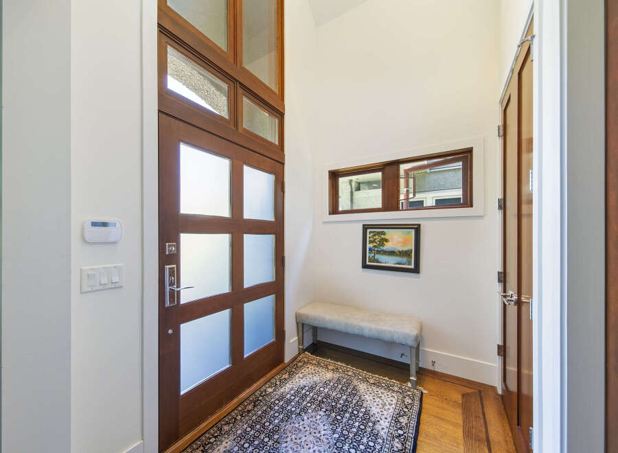 Step into this inviting entryway featuring a stunning wooden door with frosted glass panels, offering both privacy and natural light.