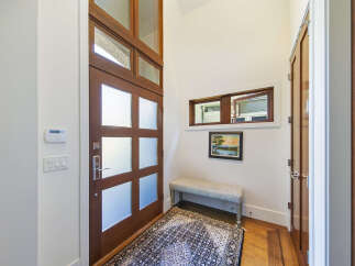 Step into this inviting entryway featuring a stunning wooden door with frosted glass panels, offering both privacy and natural light.