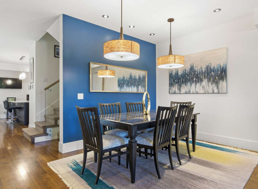 This elegant dining room features a sleek black dining table with six chairs, illuminated by two stylish pendant lights.