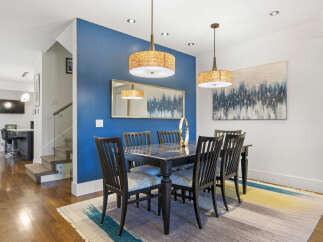 This elegant dining room features a sleek black dining table with six chairs, illuminated by two stylish pendant lights.