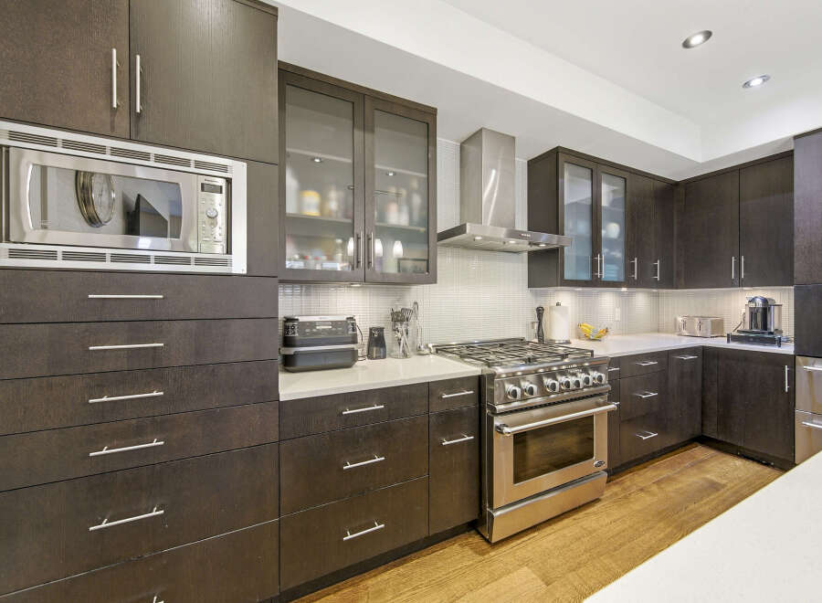 Experience culinary excellence in this modern kitchen, featuring sleek dark wood cabinetry and a professional-grade stainless steel gas range.