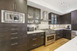 Experience culinary excellence in this modern kitchen, featuring sleek dark wood cabinetry and a professional-grade stainless steel gas range.