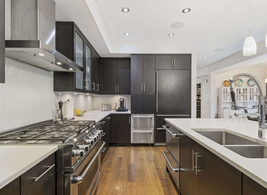Experience luxury in this modern kitchen featuring sleek dark wood cabinetry and a professional-grade gas range.