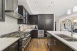 Experience luxury in this modern kitchen featuring sleek dark wood cabinetry and a professional-grade gas range.