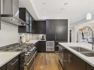 Experience luxury in this modern kitchen featuring sleek dark wood cabinetry and a professional-grade gas range.