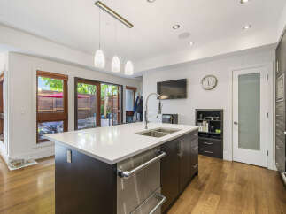 Experience modern living in this stunning kitchen featuring a large island with a double sink and sleek cabinetry.