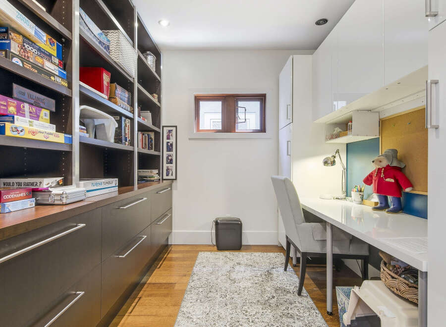 Discover a versatile space perfect for work and play, featuring extensive built-in shelving for games and books, complemented by a sleek modern desk area.
