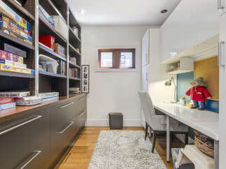 Discover a versatile space perfect for work and play, featuring extensive built-in shelving for games and books, complemented by a sleek modern desk area.