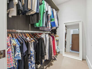 Step into this spacious walk-in closet, featuring ample hanging space for your wardrobe and a full-length mirror to complete your look.