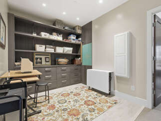 Discover this organized craft room featuring ample storage with floor-to-ceiling dark wood shelving and drawers.