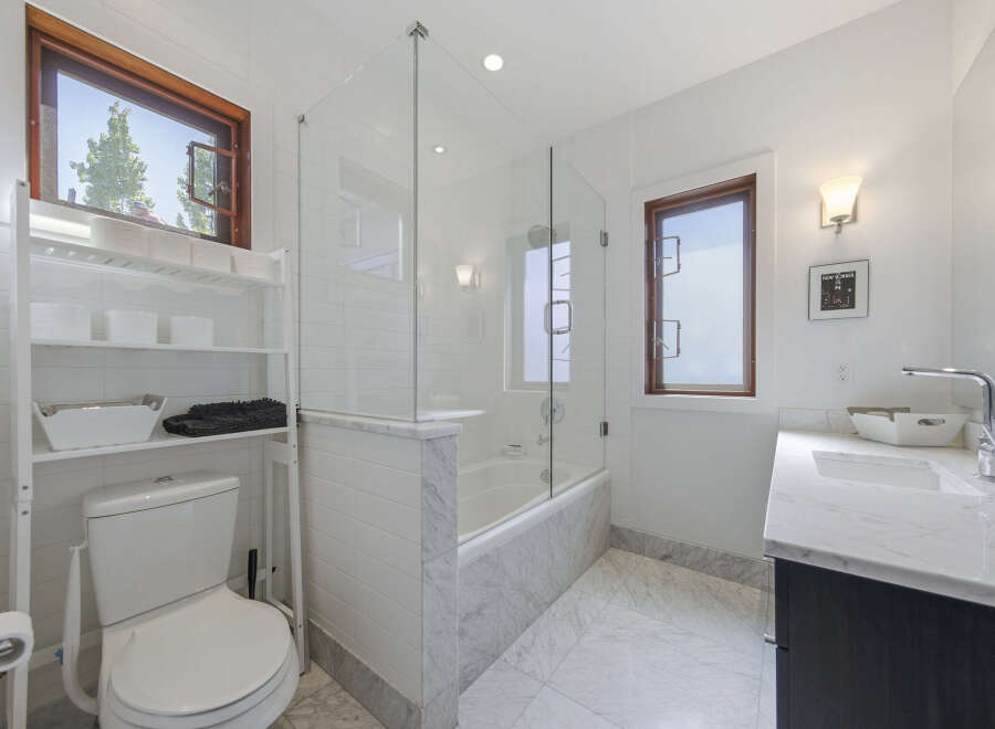 This modern bathroom features a sleek design with a freestanding bathtub enclosed by a glass shower door.