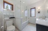 This modern bathroom features a sleek design with a freestanding bathtub enclosed by a glass shower door.