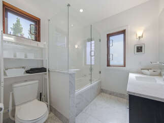 This modern bathroom features a sleek design with a freestanding bathtub enclosed by a glass shower door.