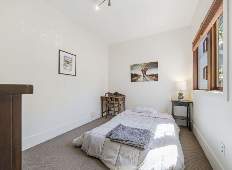 Discover this charming bedroom featuring a comfortable bed with soft linens and a cozy throw blanket.