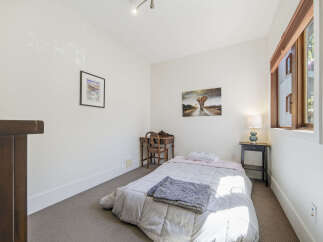 Discover this charming bedroom featuring a comfortable bed with soft linens and a cozy throw blanket.