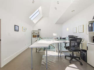 This bright and airy home office features a modern white L-shaped desk with ample workspace, complemented by a comfortable black ergonomic chair.