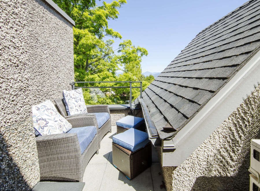 Enjoy your morning coffee or evening relaxation on this charming balcony, featuring comfortable wicker seating with plush blue cushions and decorative pillows.