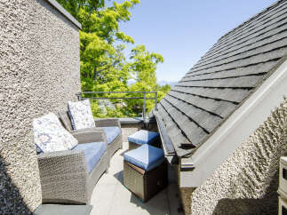 Enjoy your morning coffee or evening relaxation on this charming balcony, featuring comfortable wicker seating with plush blue cushions and decorative pillows.