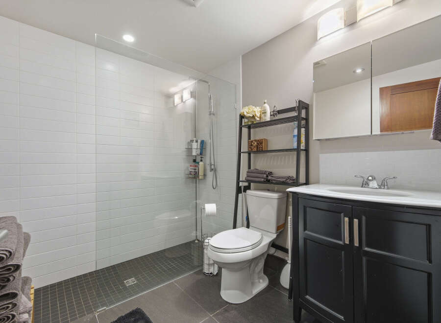 This modern bathroom features a spacious walk-in shower with white subway tile walls and a sleek glass enclosure.