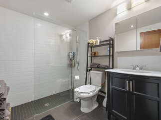 This modern bathroom features a spacious walk-in shower with white subway tile walls and a sleek glass enclosure.
