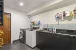 This laundry room features a sleek, modern design with a stainless steel washing machine and a white top-load washer.