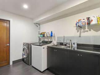 This laundry room features a sleek, modern design with a stainless steel washing machine and a white top-load washer.