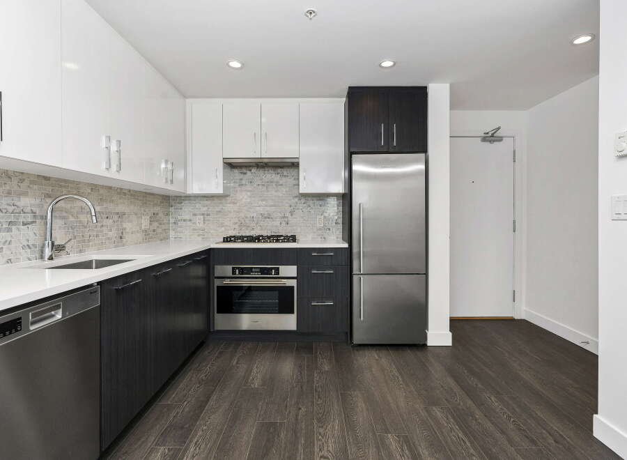 Experience modern living in this sleek kitchen featuring high-gloss white cabinetry and dark wood lower cabinets.