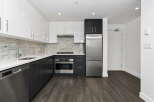 Experience modern living in this sleek kitchen featuring high-gloss white cabinetry and dark wood lower cabinets.