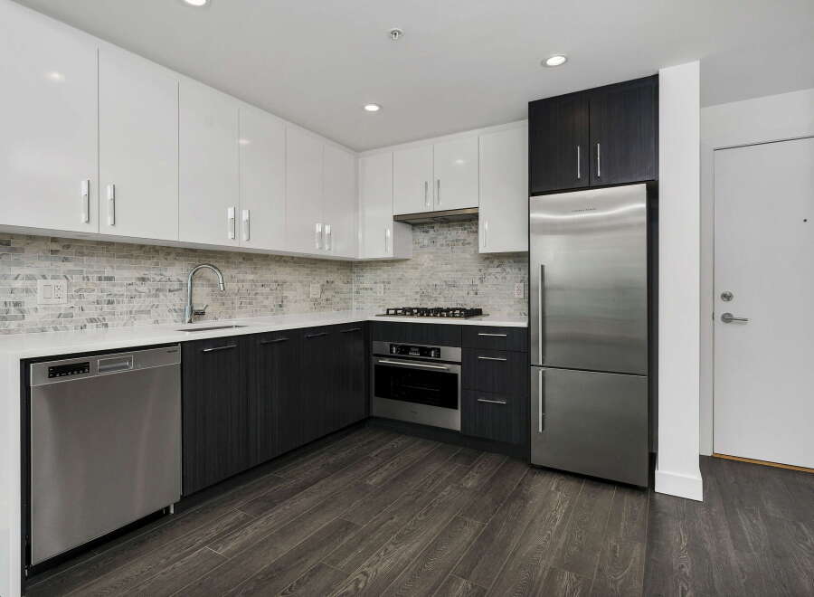 Experience modern living in this sleek kitchen featuring high-gloss white cabinetry and dark wood lower cabinets.
