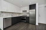 Experience modern living in this sleek kitchen featuring high-gloss white cabinetry and dark wood lower cabinets.