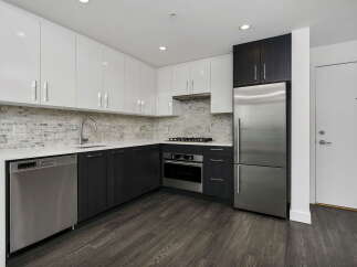 Experience modern living in this sleek kitchen featuring high-gloss white cabinetry and dark wood lower cabinets.