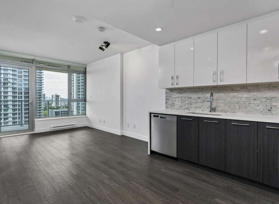 Experience modern living in this spacious apartment featuring a sleek kitchen with white cabinetry, a marble backsplash, and stainless steel appliances.