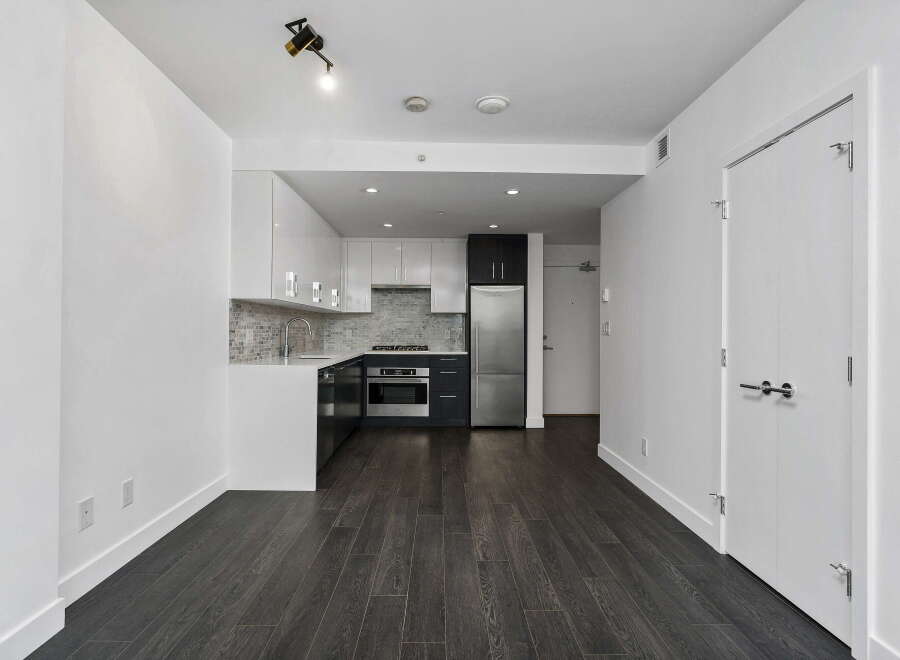 Discover modern living in this stylish condo featuring a sleek, contemporary kitchen with stainless steel appliances and a mosaic tile backsplash.
