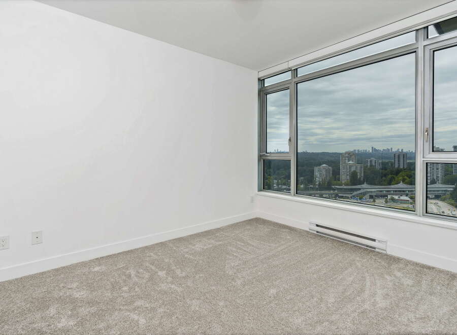 Experience breathtaking city views from this spacious room, featuring a wall-to-wall carpet and a large window that floods the space with natural light.