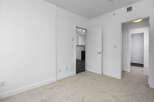 Step into this bright and airy living space, featuring plush carpeting and clean white walls for a modern aesthetic.