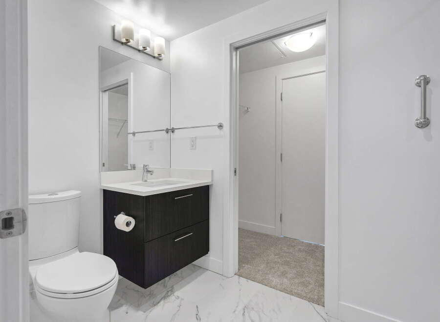 Experience modern comfort in this pristine bathroom, featuring a sleek dark wood vanity with a white countertop and integrated sink.