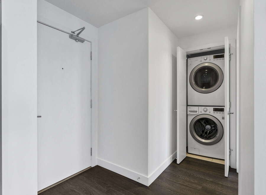 Discover modern convenience with this stacked LG washer and dryer set, neatly tucked away behind bi-fold doors.