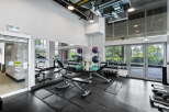 This modern gym features a variety of equipment, including treadmills, weight benches, and a comprehensive dumbbell rack.
