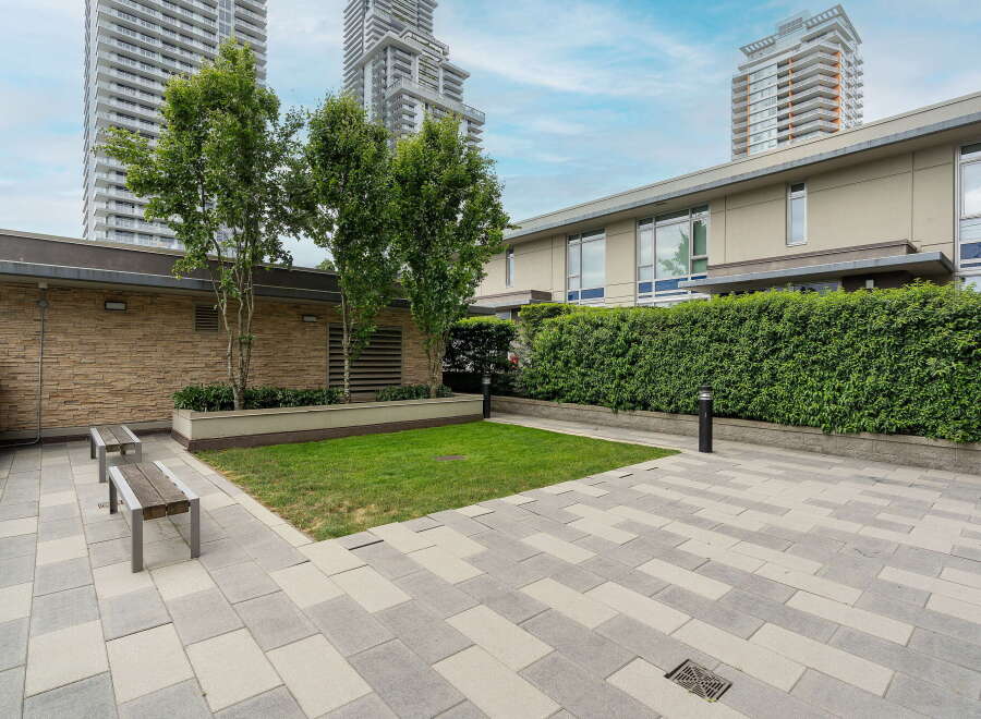 Enjoy outdoor living in this modern courtyard featuring a lush green lawn and stylish paved patio.