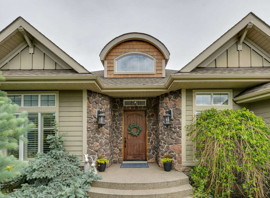 This charming home features a welcoming stone entryway leading to a beautiful wooden door adorned with a festive wreath.