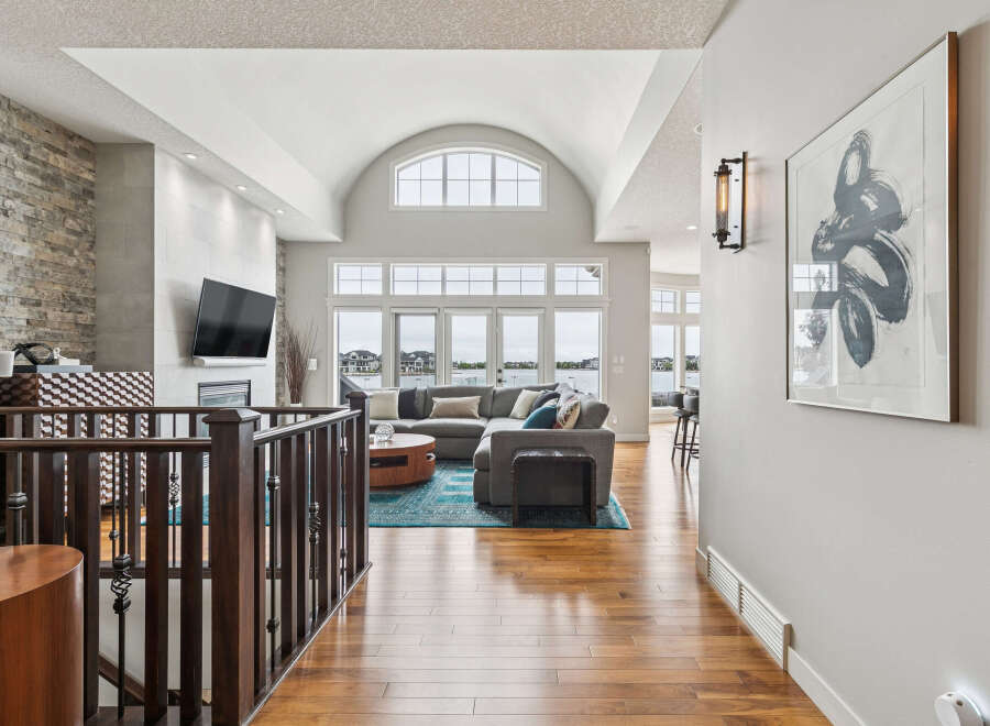 Experience luxury living in this stunning home featuring a grand, vaulted ceiling living area with a wall of windows overlooking the water.
